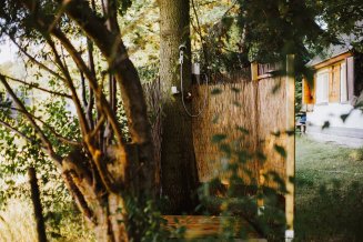 Tragbare Dusche mit Cointra Durchlauferhitzer in einem Garten an einen Baum montiert